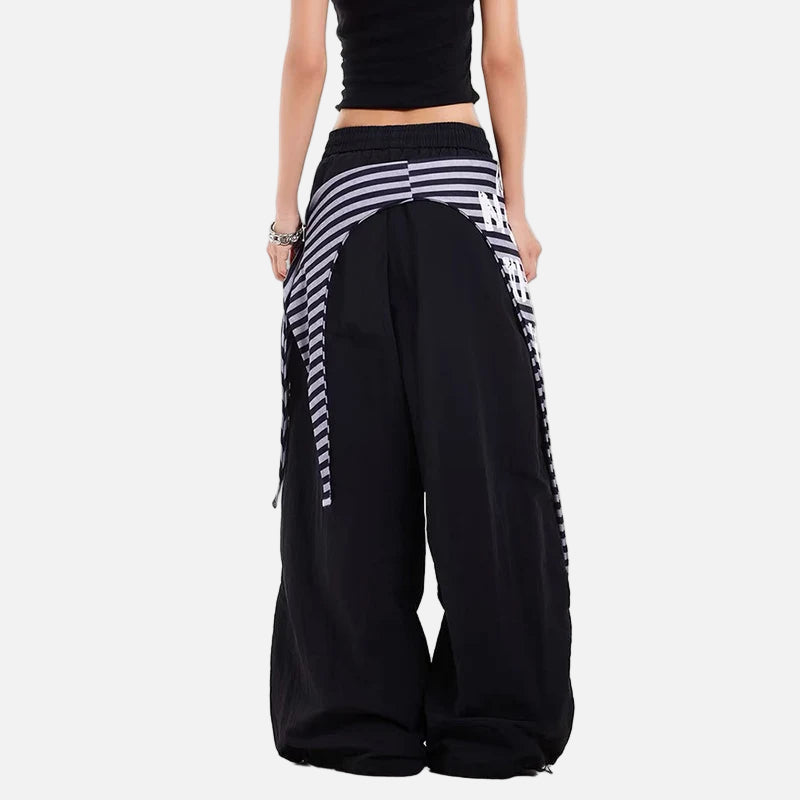 Black wide-leg pants with white striped side panels worn by a person on a white background
