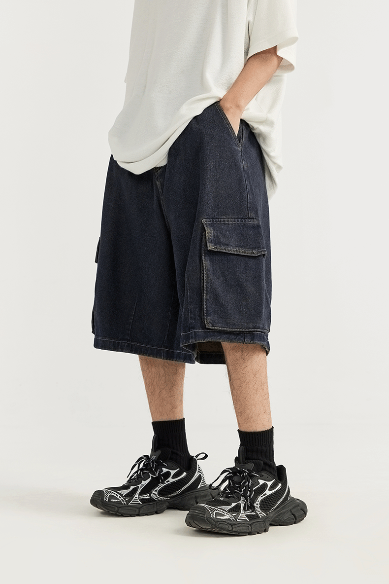 A model wearing the dark blue Vintage Denim Cargo Jorts in a gray background