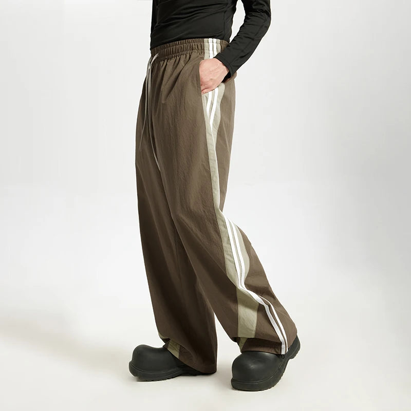 Model wearing the brown Stride Luxe Pants in a gray background