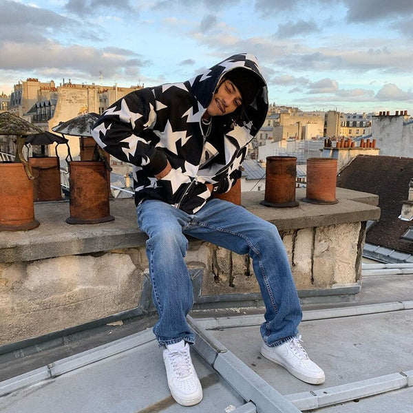 A model wearing the black Zip Up Grunge Hoodie while sitting on the roof of a building