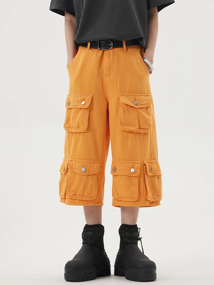 A model wearing the orange Heavy-duty Multi-pocket Cargo Jorts in a gray background 