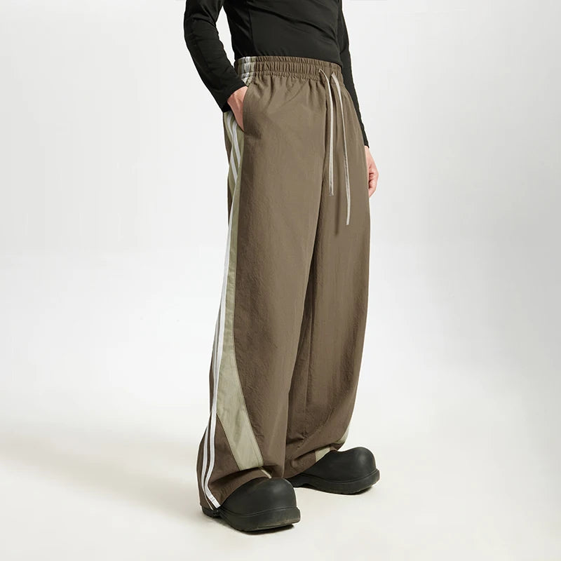 Model wearing the brown Stride Luxe Pants in a gray background