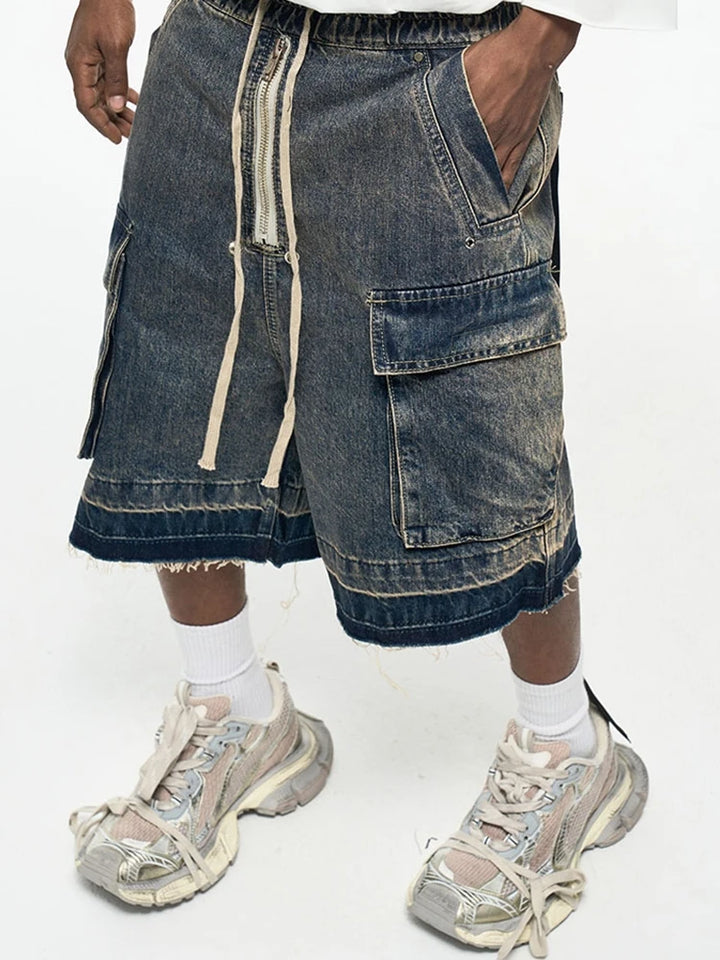 A model wearing the blue Zip-Up Loose Washed Pocket Jorts in a gray background