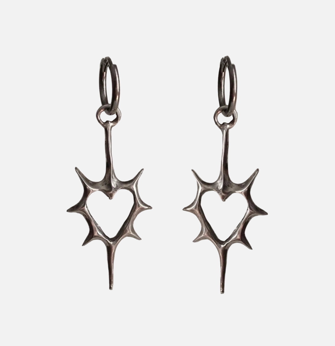 Front view of the heart Stellar Edge Earrings in a gray background