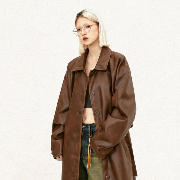 Model wearing the brown Y2k Solid Color Leather Coat in a gray background 