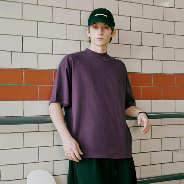 A model standing in the subway while wearing the High-neck Respecting Solid Loose T-shirt from DAXUEN.