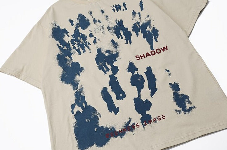 A beige T-shirt featuring a distressed blue graphic print with abstract human figures and the words "SHADOW" and "FEELINGS IMAGE" in red text, highlighting a unique streetwear design
