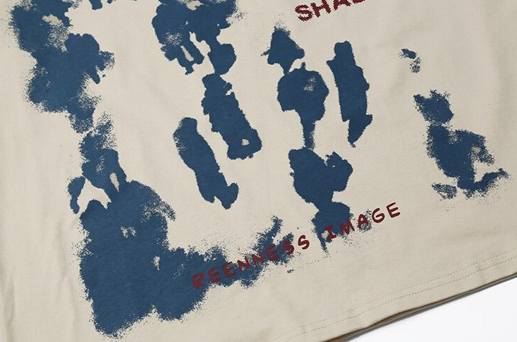 Beige T-shirt with distressed blue abstract prints, "SHADOW" and "FEELNESS IMAGE" red text, streetwear style.